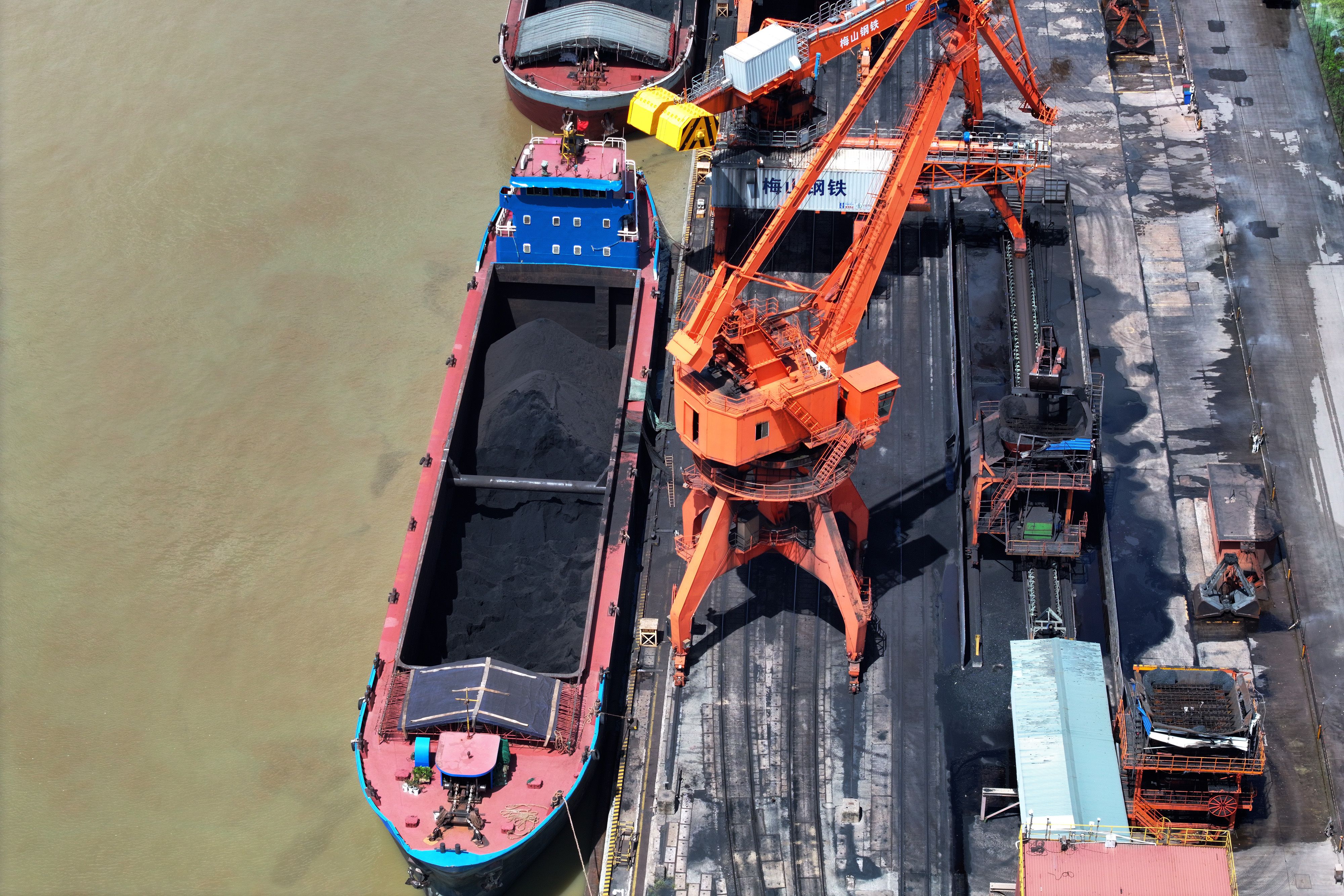 Краны выгружают уголь с грузового судна Краны выгружают уголь с грузового судна